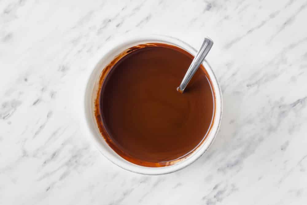 Melted chocolate in a white bowl with a spoon.