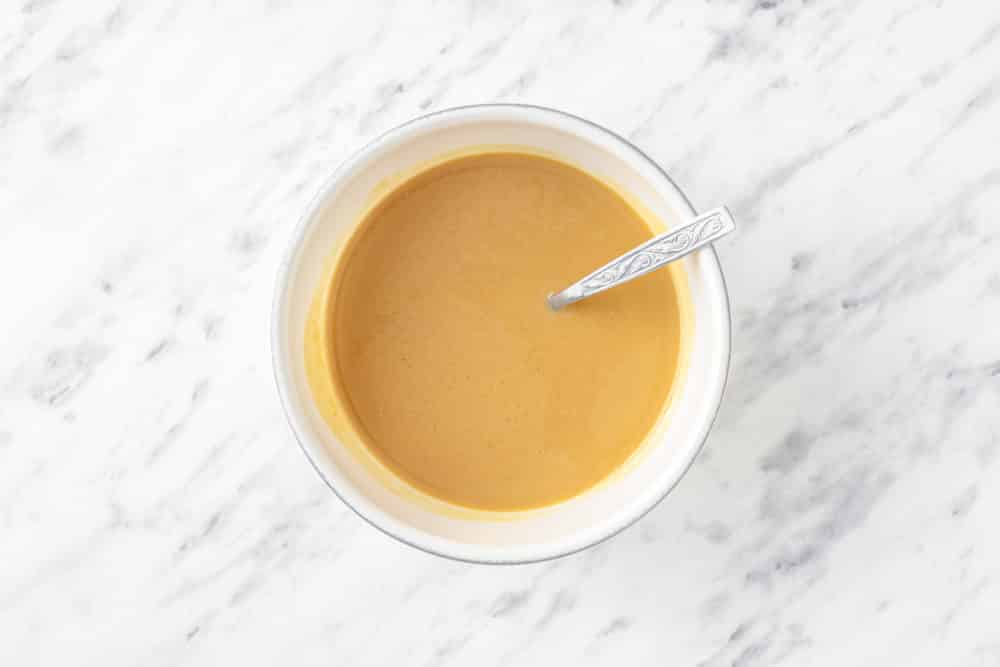 Melted peanut butter with a spoon in a bowl.