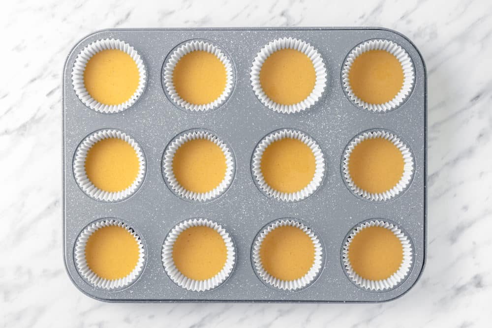 Peanut butter in white cups in a grey muffin tin.