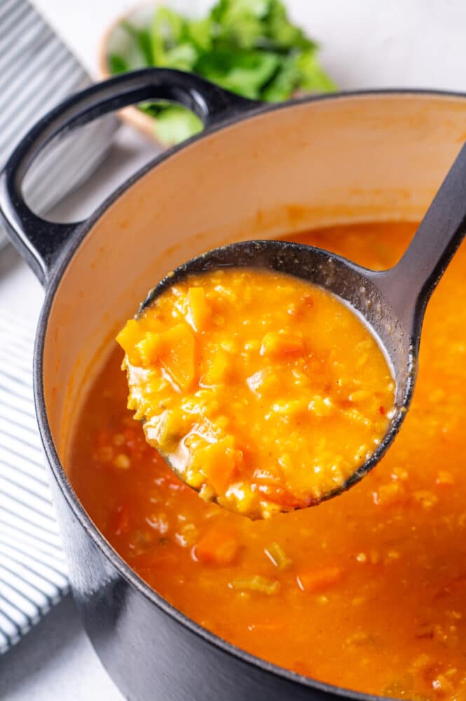 Ladling soup from a large black pot.