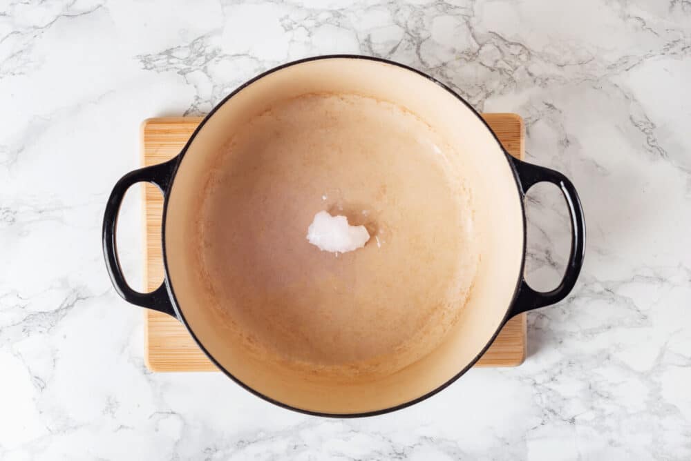 Coconut oil in a soup pot on a wooden board.