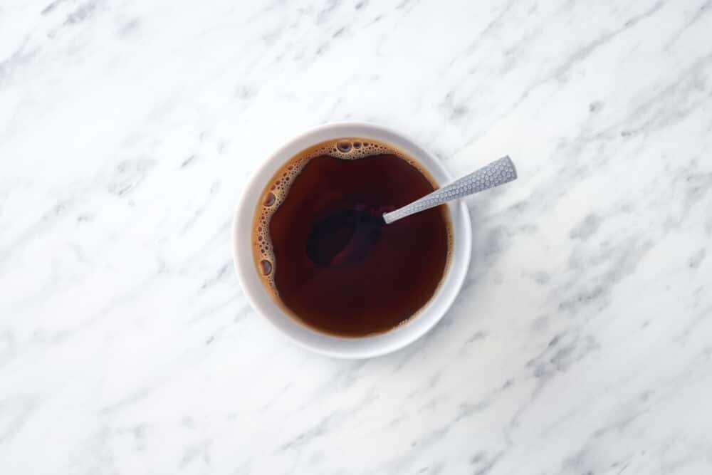 Coffee mixing with coffee liqueur in a white bowl with a spoon.