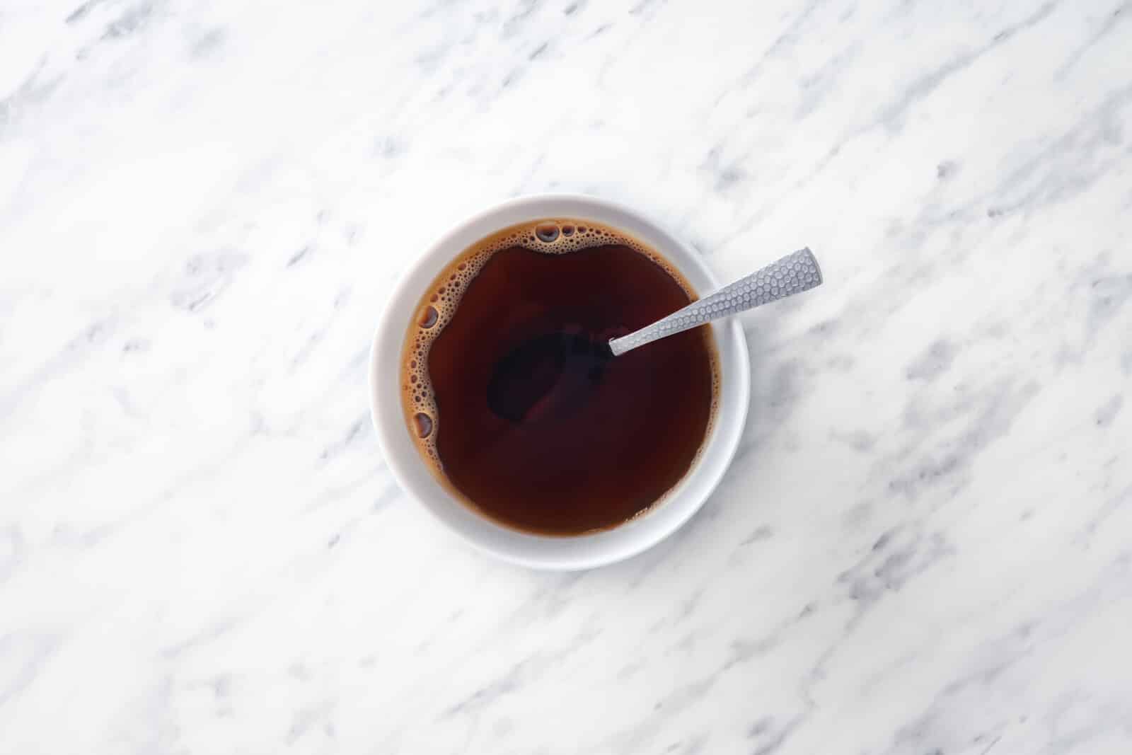 Coffee mixing with coffee liqueur in a white bowl with a spoon.