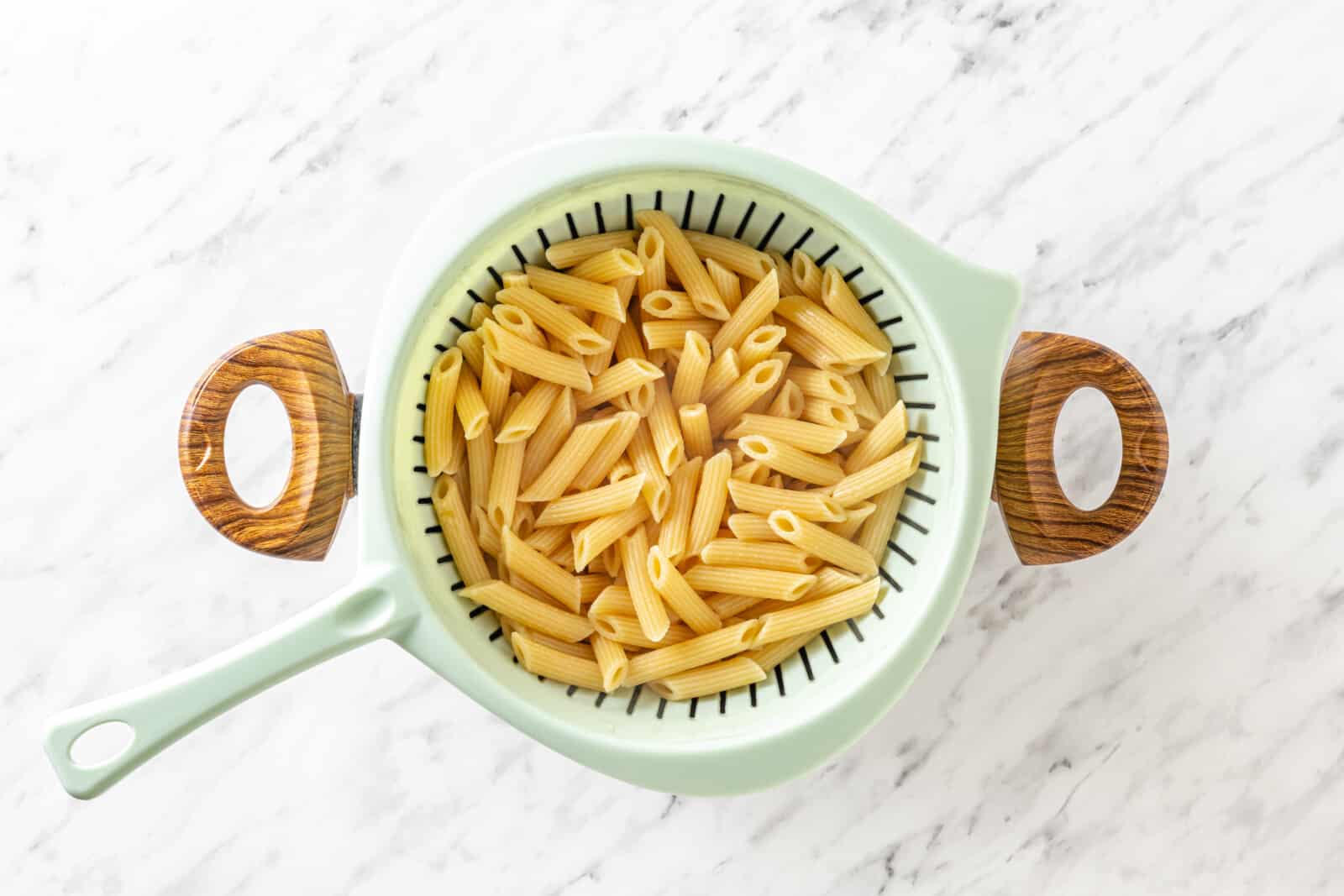 Cooked pasta in a sieve over a pot.