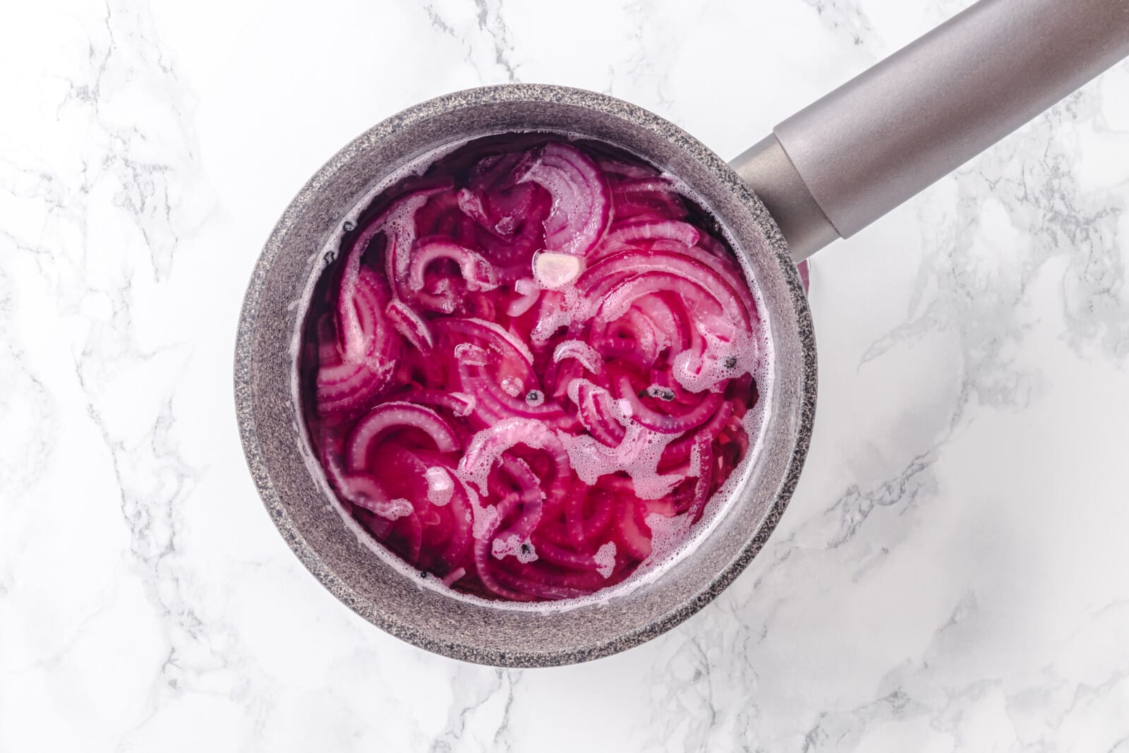 Cooking pickled onions in a saucepan.