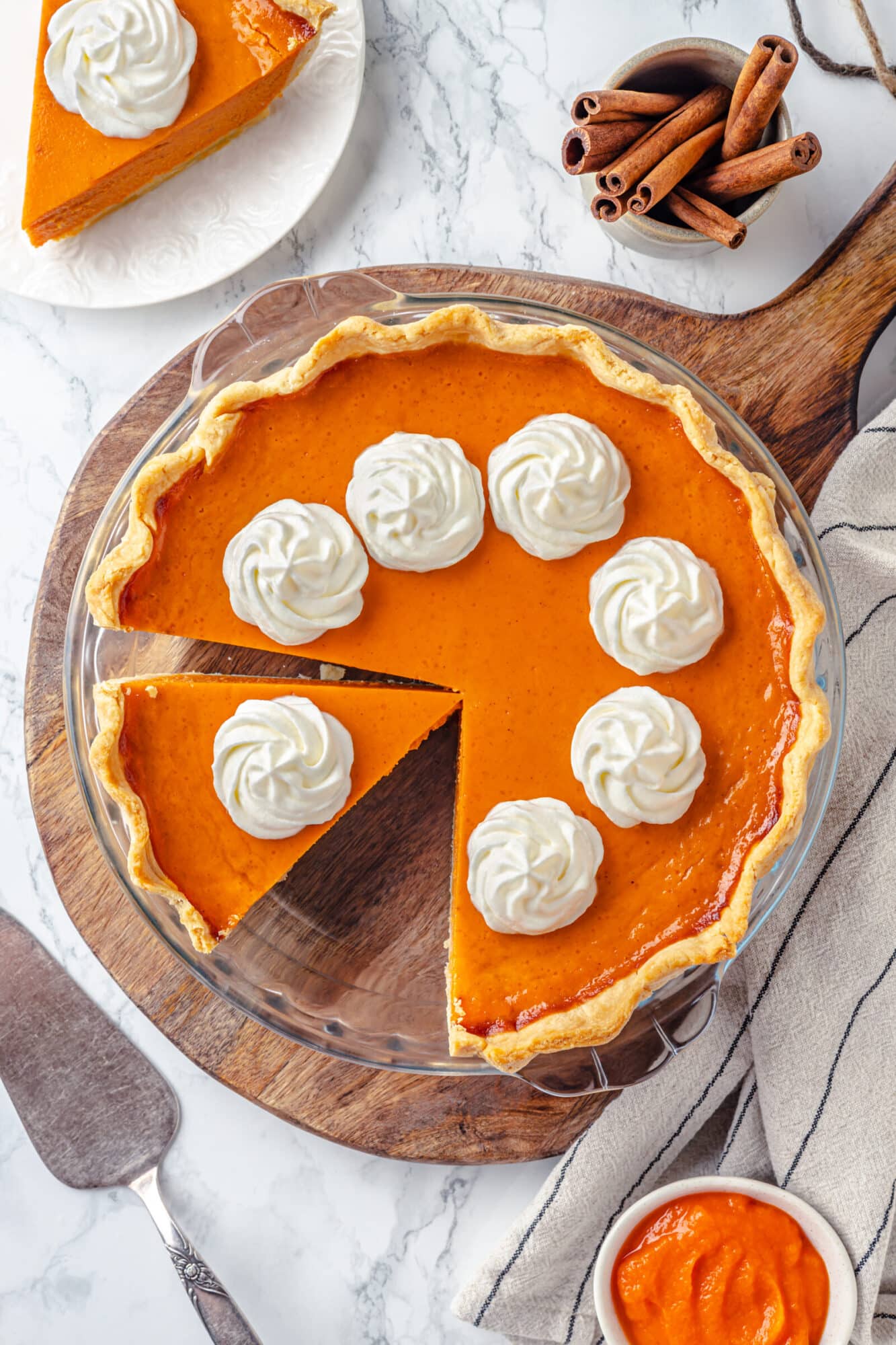 Cutting slices of pumpkin pie to serve on white plates.