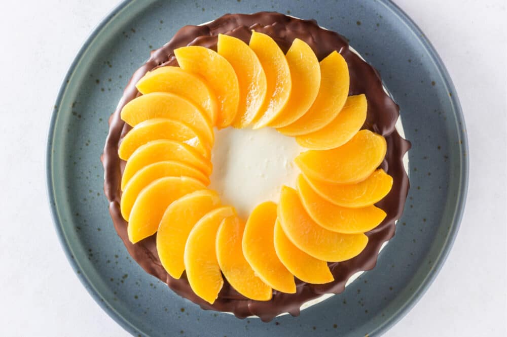 Decorating cake with melted chocolate and peach slices.