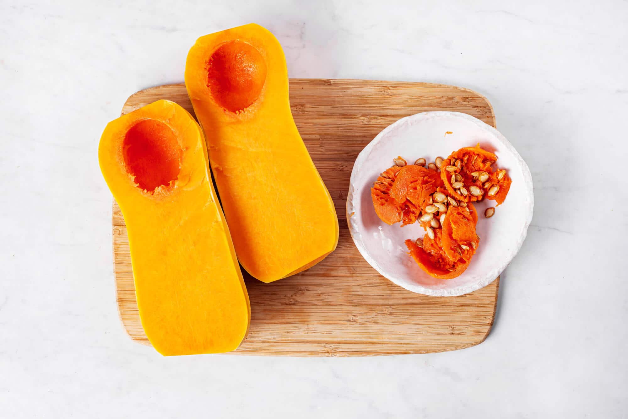 butternut-squash-halves-on-a-wooden-board-cored-with-a-white-bowl-on-the-side