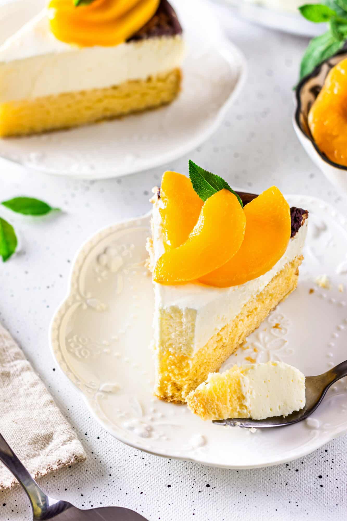 Eating peach cake with a fork, decorated with peach slices and mint garnish.