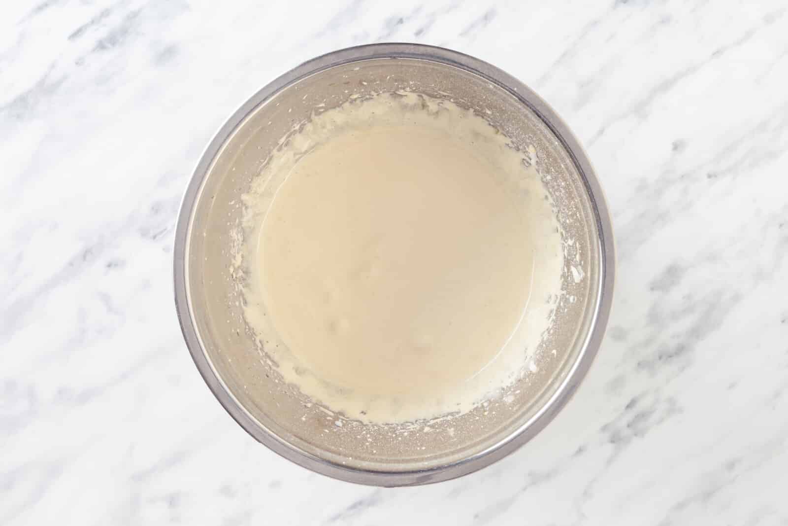 Egg yolks and sugar mixed in a silver mixer bowl.