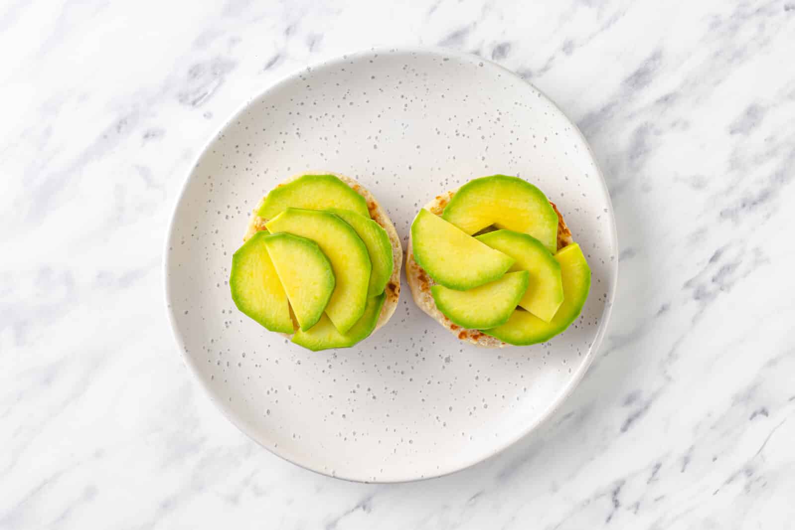 avocado slices on top of two halves of english muffins