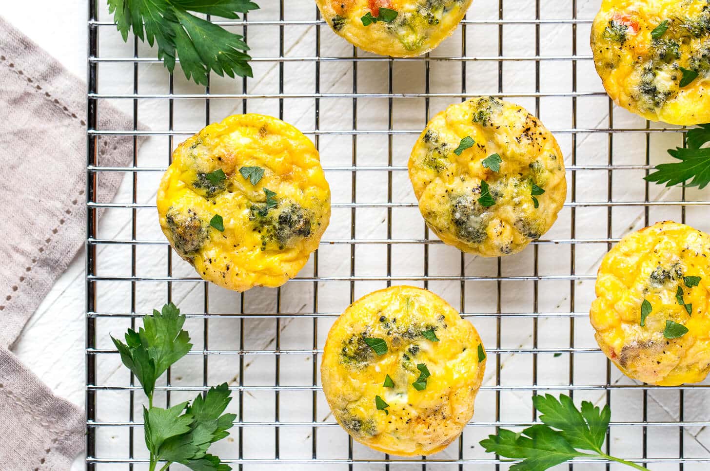 a wire rack with frittata egg muffins close up and parsley.