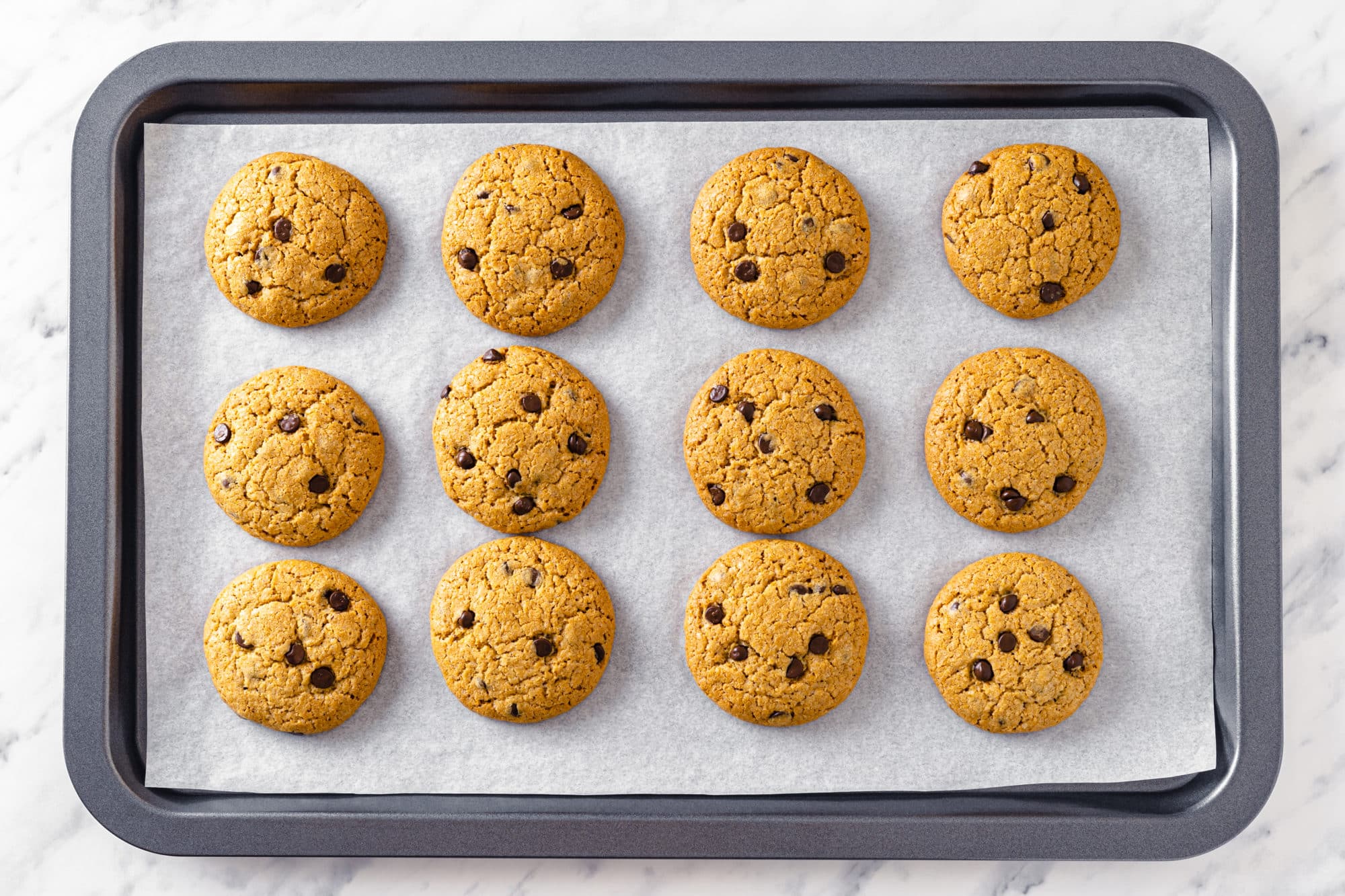 baked chocolate chip cookies on parchment paper and a baking tray.