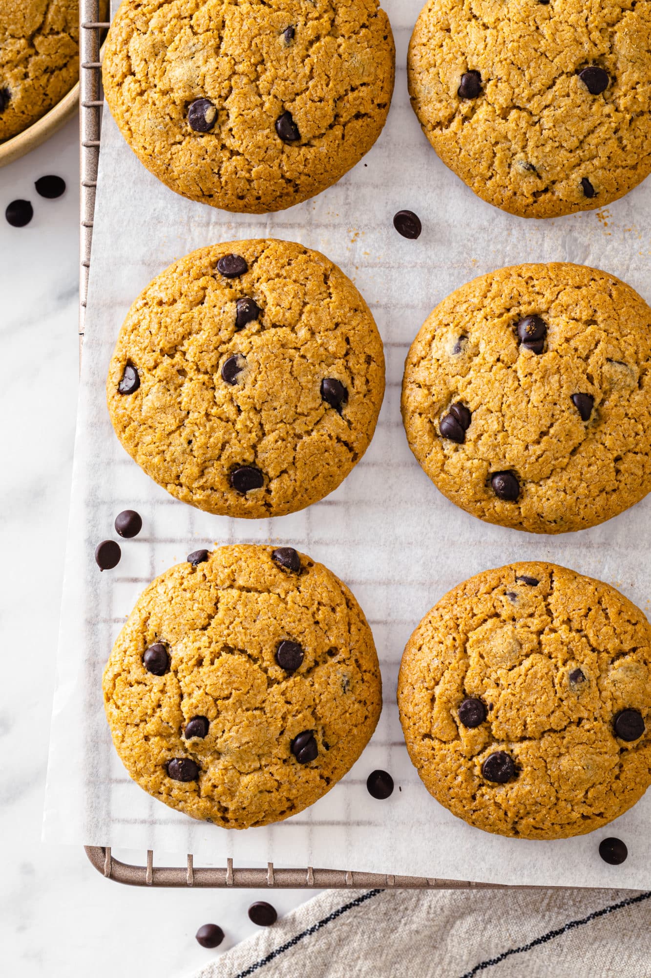 baked chocolate cookies cooling on a rack with a brown linen towel on the side. 