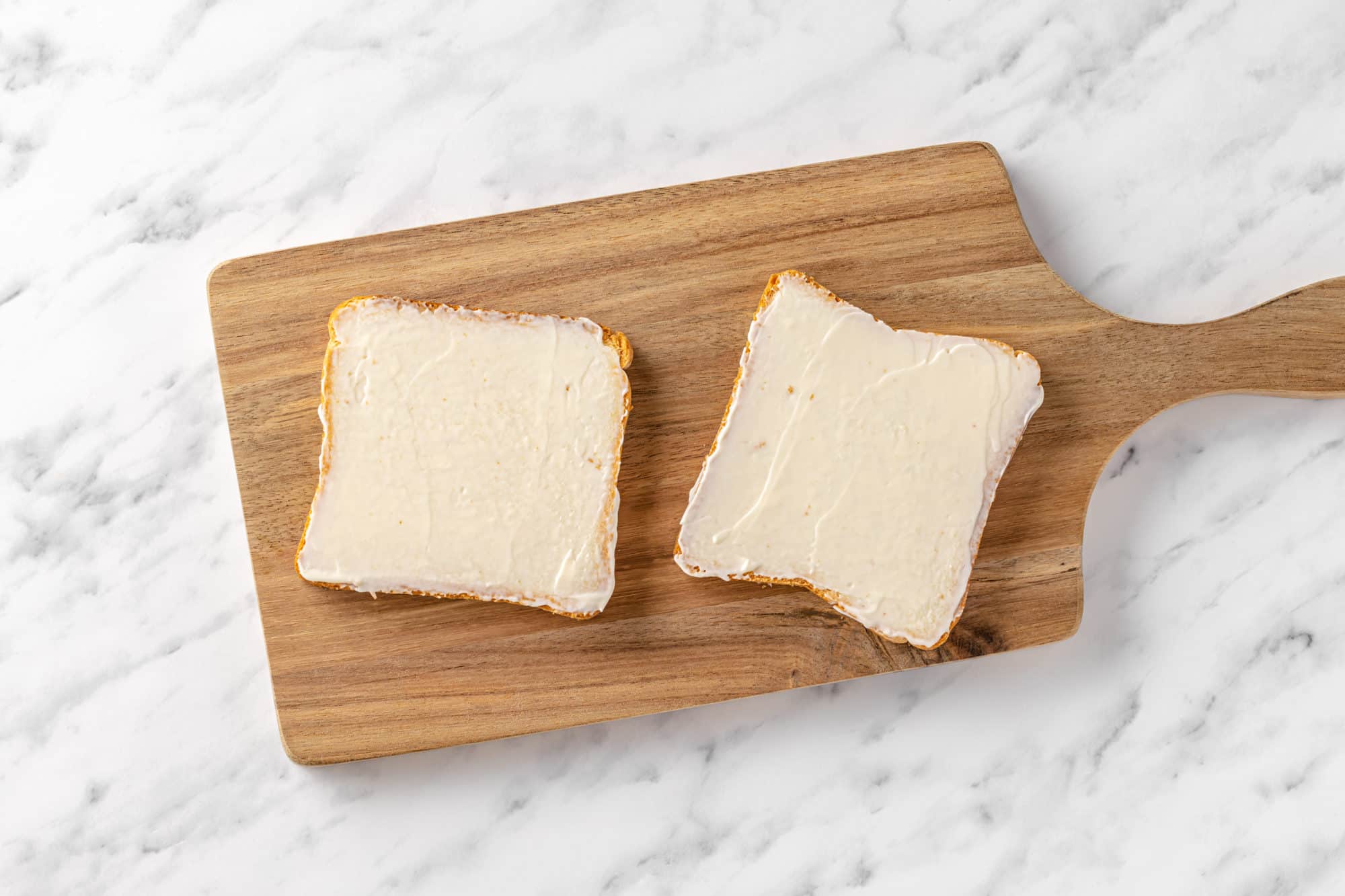 bread slices with mayonnaise on a wooden board.