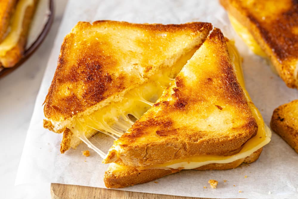 Sliced grilled cheese sandwiches on parchment paper.