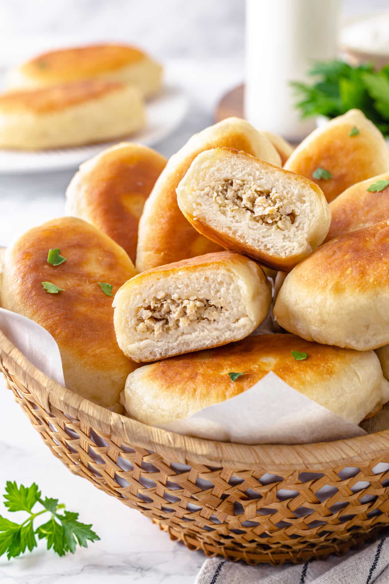 Halved piroshki atop a bowl of more piroshki.