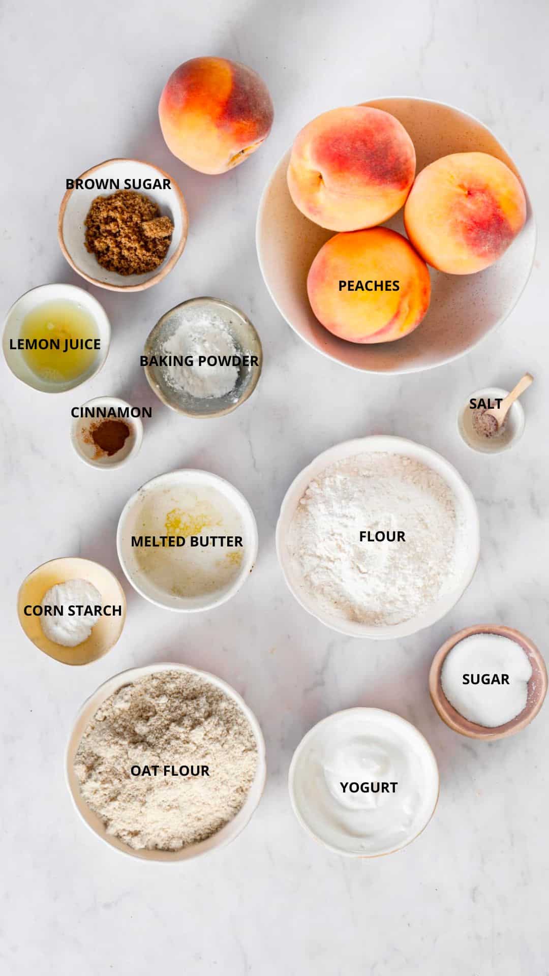 Peach Cobbler ingredients- peaches, brown sugar, lemon juice, baking powder, cinnamon, melted butter, flour, salt, sugar, corn starch, oat flour, and yogurt.