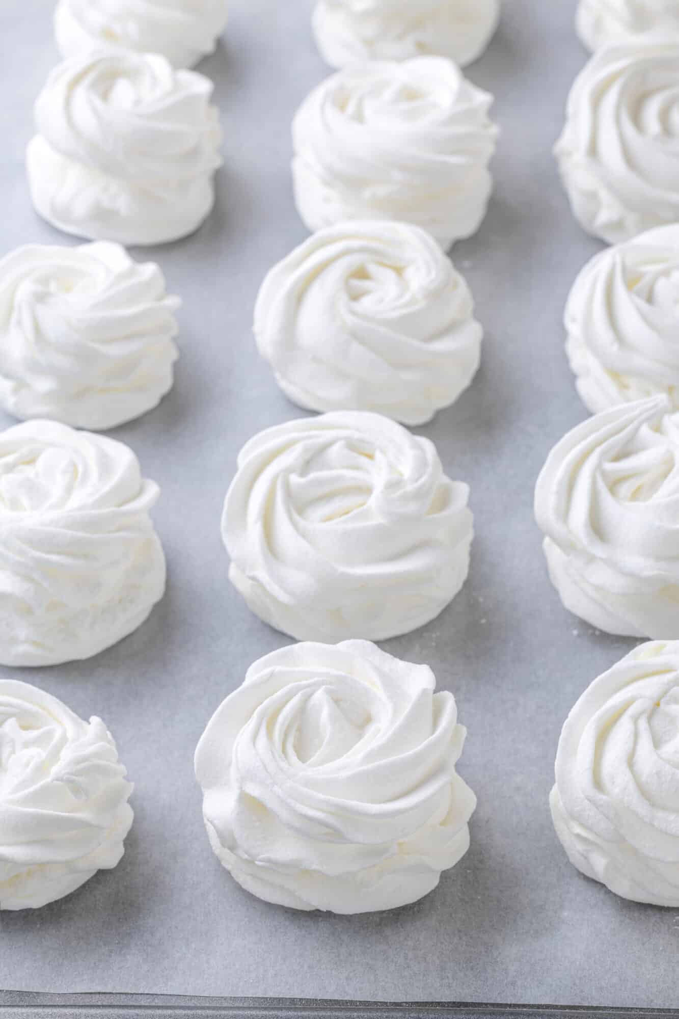 Marshmallows set on a baking tray with parchment paper.