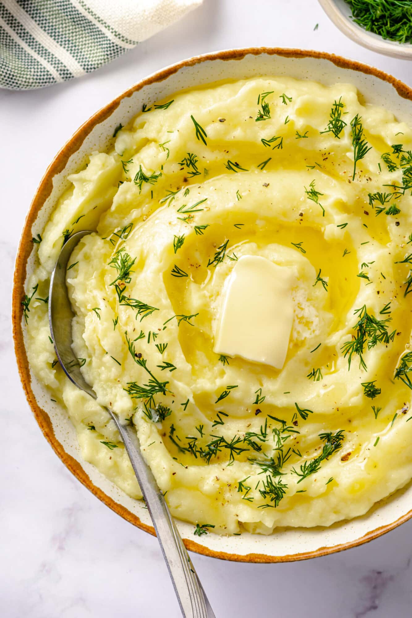 cooked buttery mashed potatoes with fresh chopped dill and butter piece in a plate. 