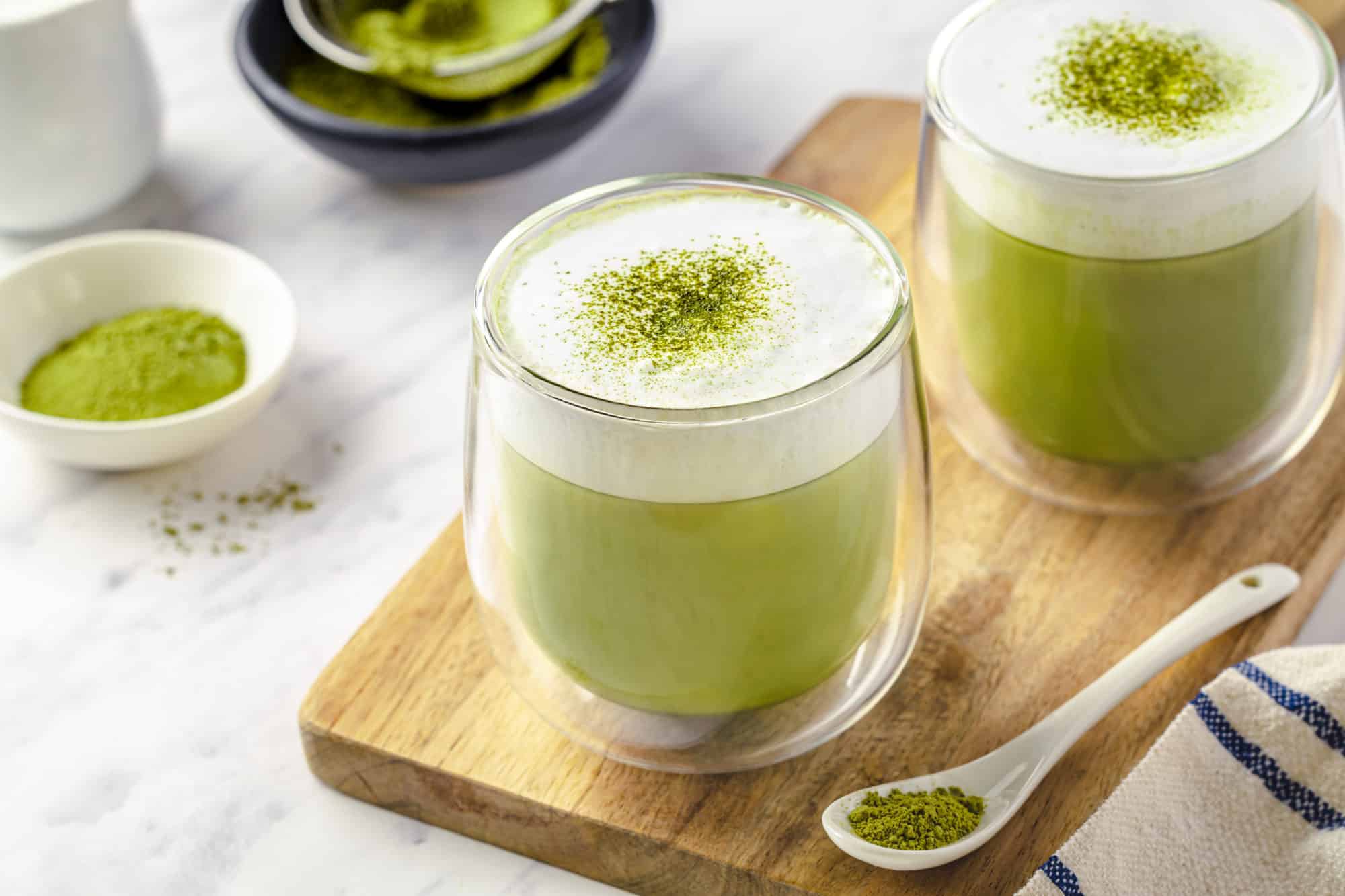 glasses filled with matcha latte with frothed milk on top.