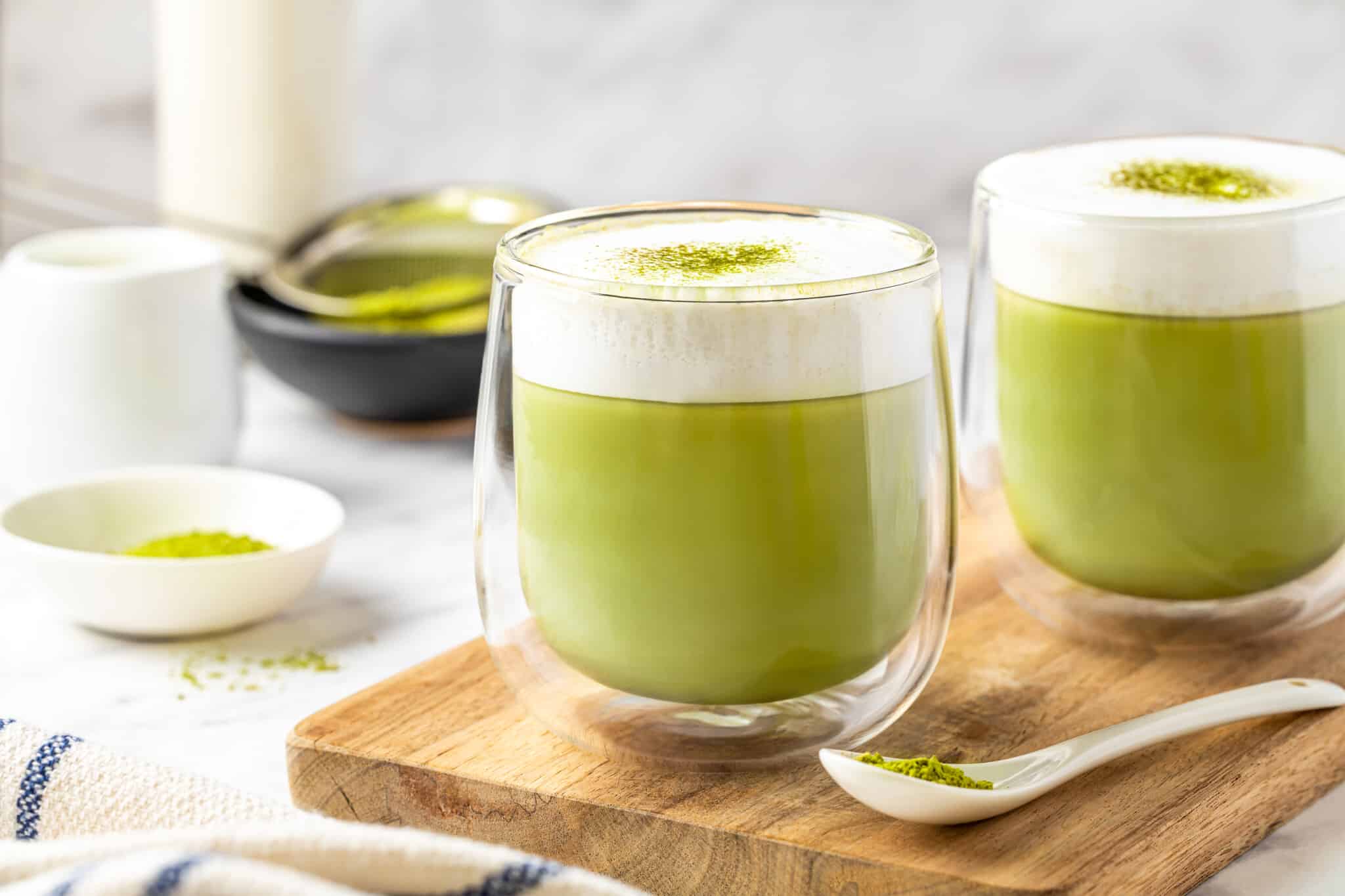 glasses filled with matcha latte with frothed milk on top.