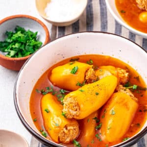 Mini stuffed peppers in a bowl with sauce.