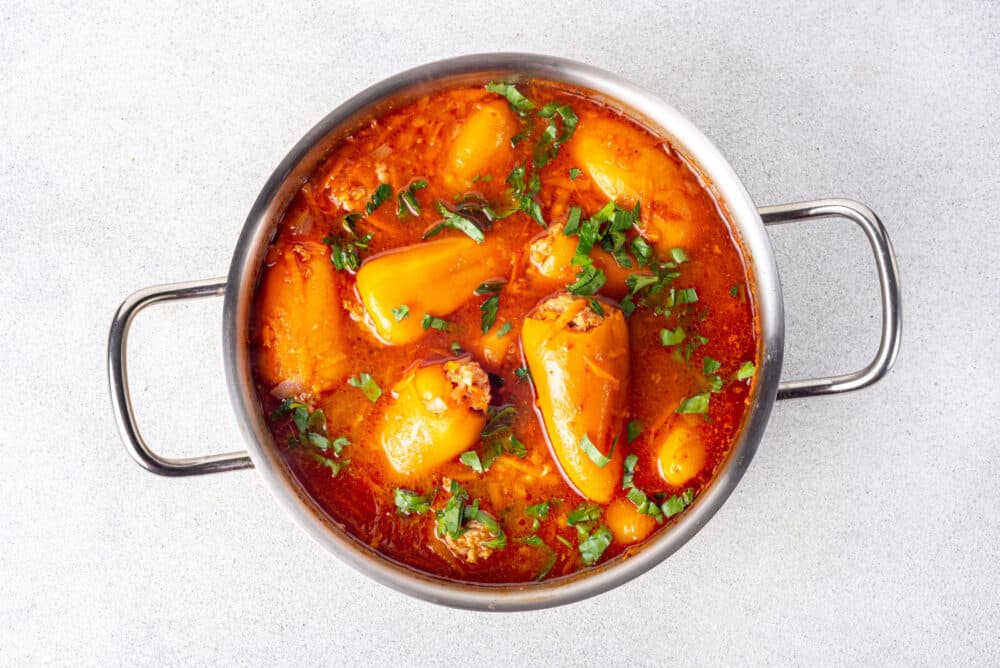 Mini stuffed peppers in a pot garnished with parsley.