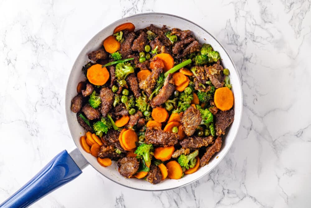 cooked beef with mixed vegetables in a pan.