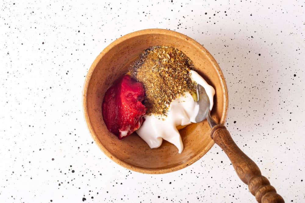 spices and mayonnaise in a brown bowl with a spoon.