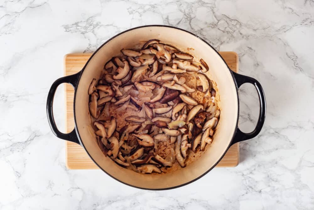 Mushrooms sauteing in a pot with onions and garlic.