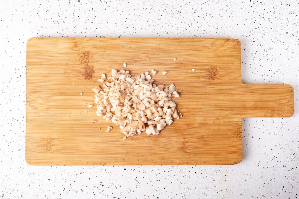 chopped mushroom stems on a wooden board.