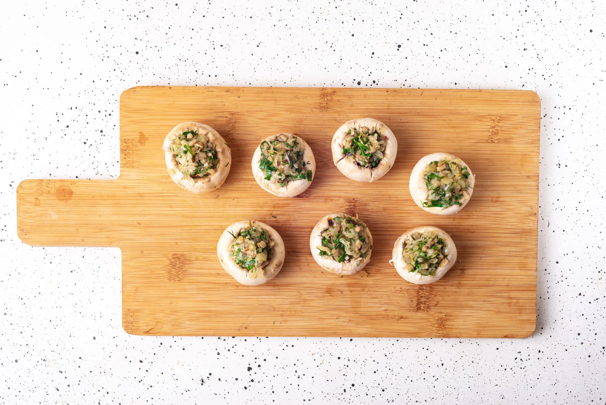 mushroom bites stuffed with filling on a wooden board.