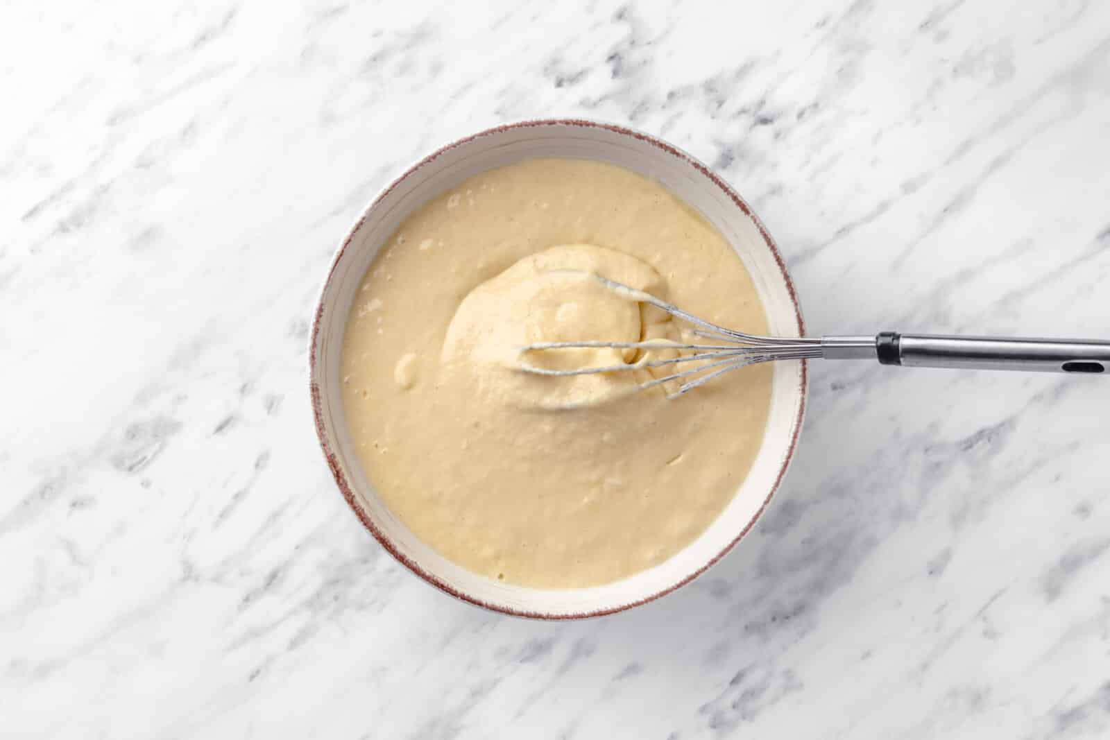 pancake batter in a bowl with a whisk resting inside it