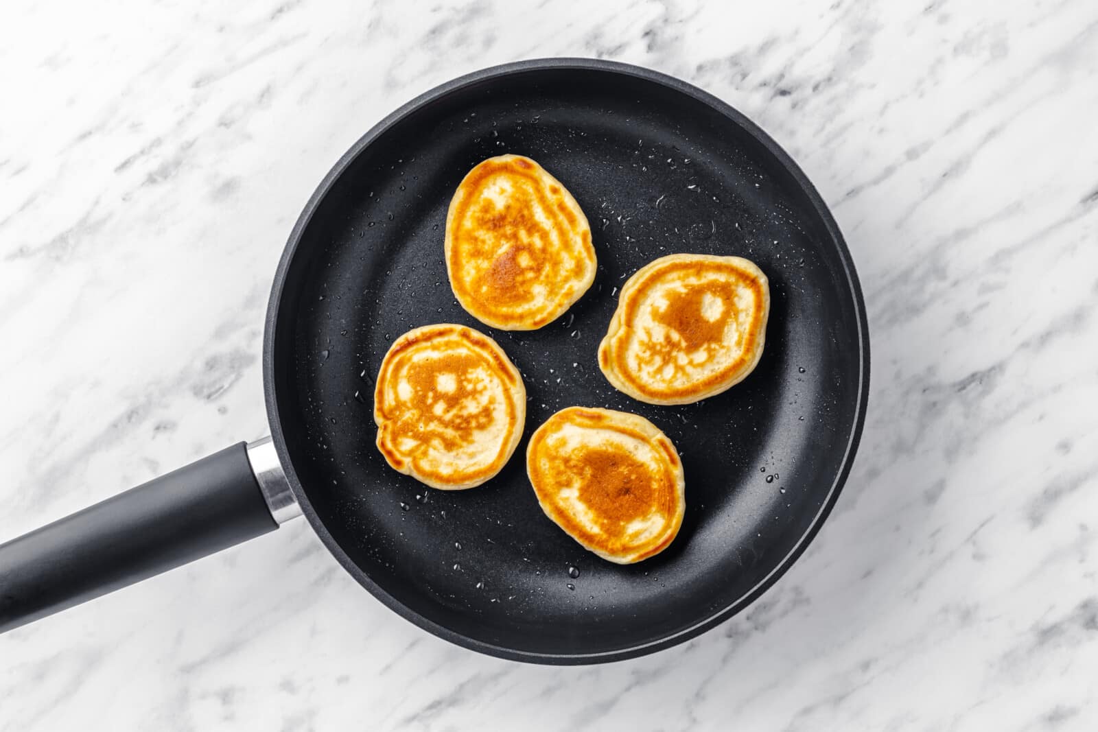 pancakes in a skillet flipped so the browned side is visible