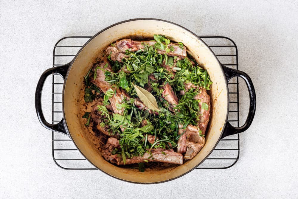 black cast iron with chopped fresh herbs bay leaf and lamb chops.