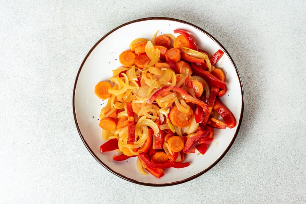 cooked veggies on a white plate with a black rim.