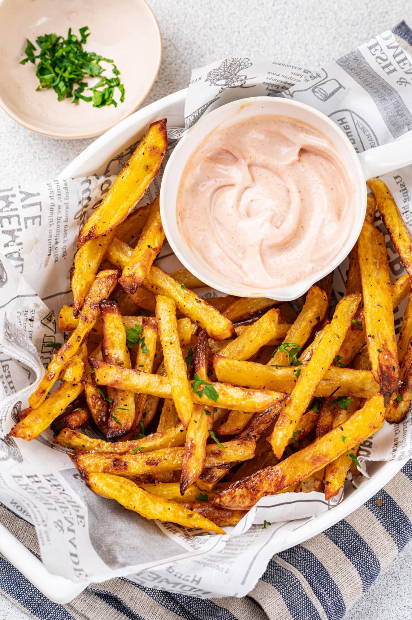 Oven roasted fries in a bowl with garnish and parsley.