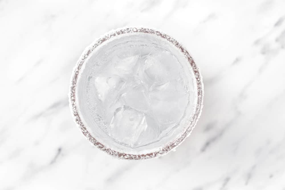 clear liquid and ice in a glass with sugar on the rim.