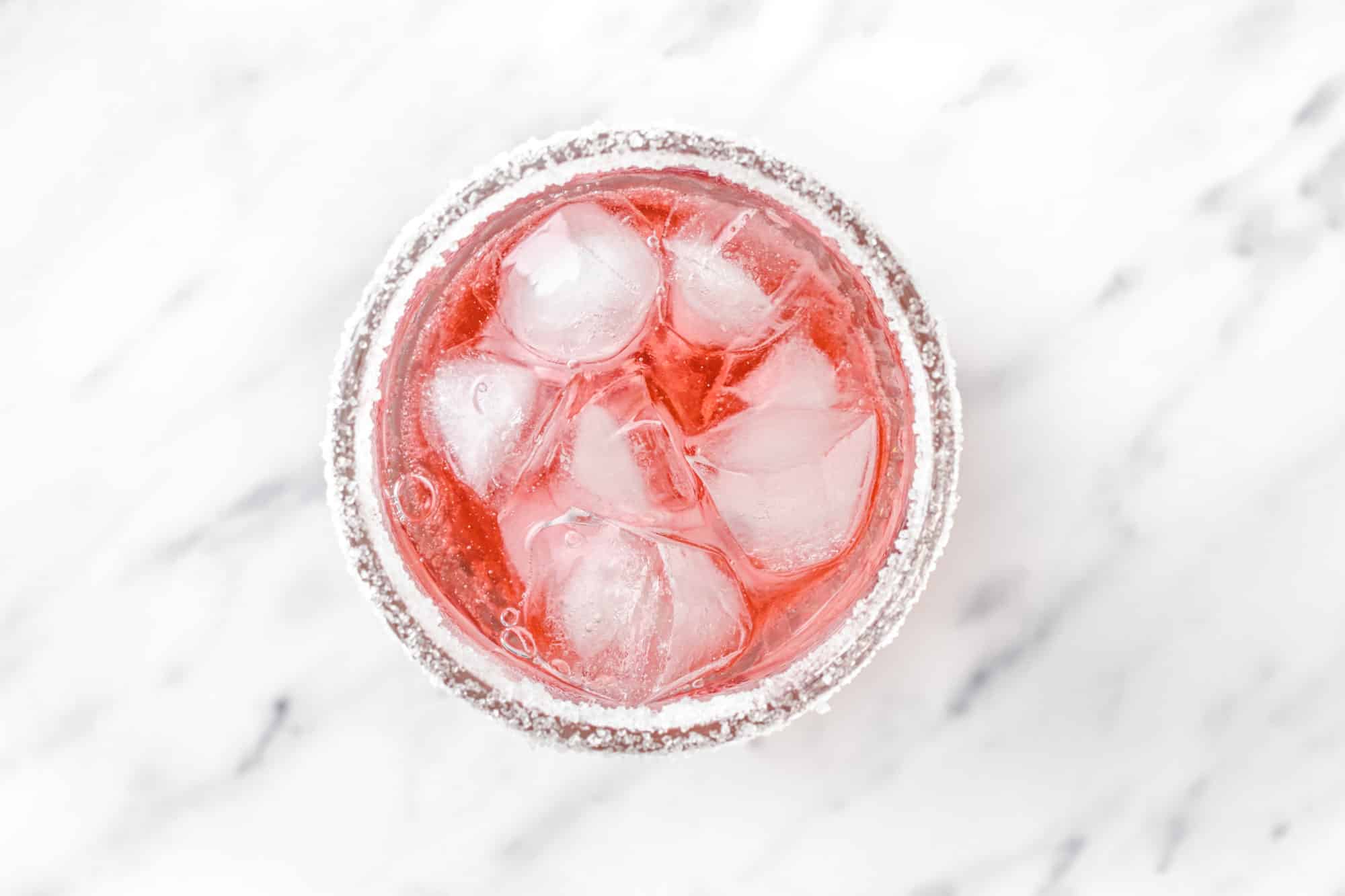 a drink being put together in a glass with ice and sugar on the rim.