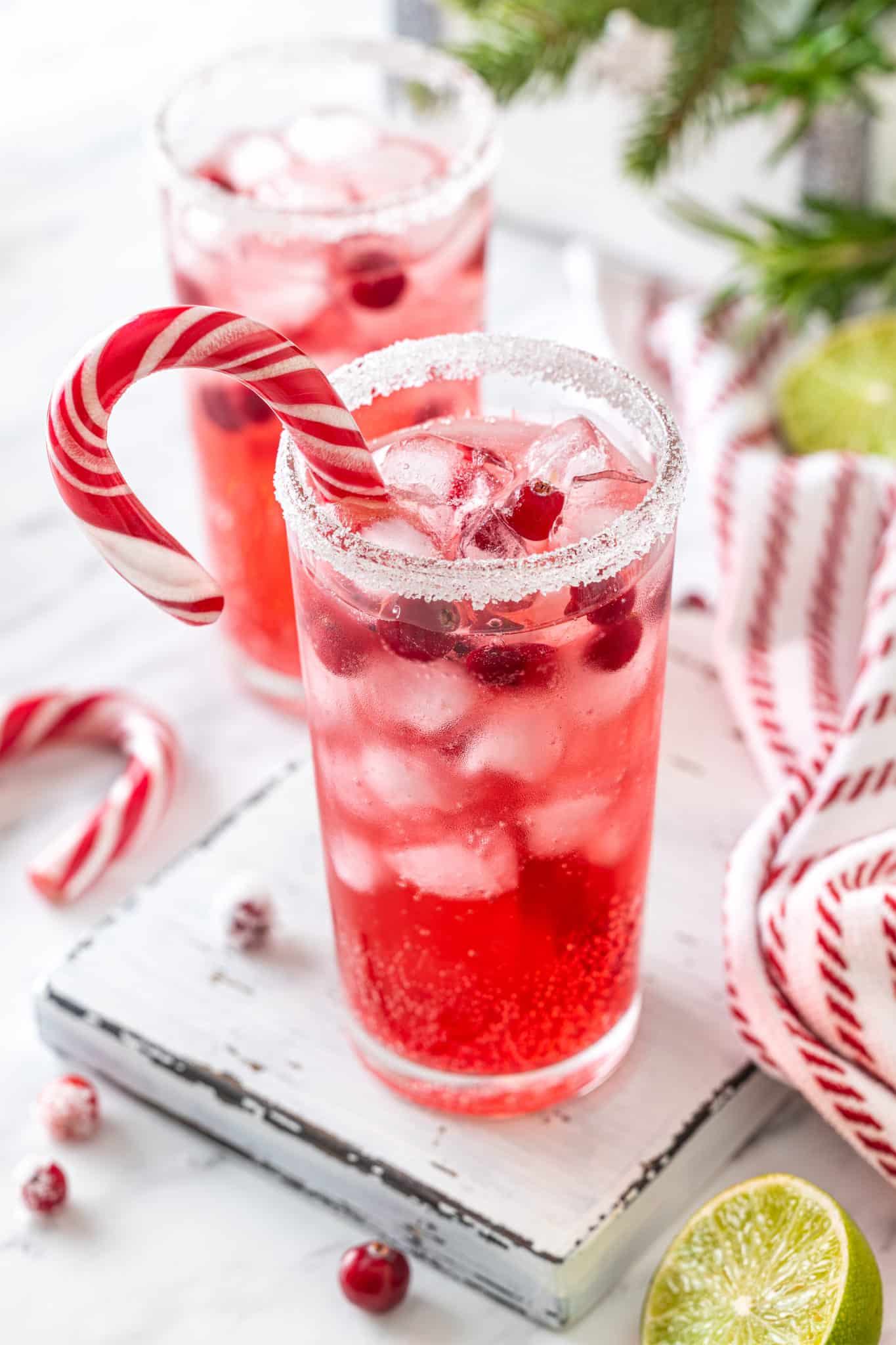 mocktail in a glass cup on a white board with a candy cane in the cup.