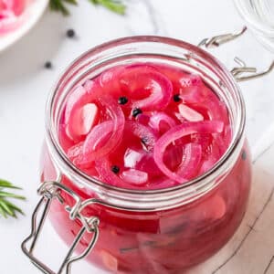 Pickled onions in a glass jar with a lid.