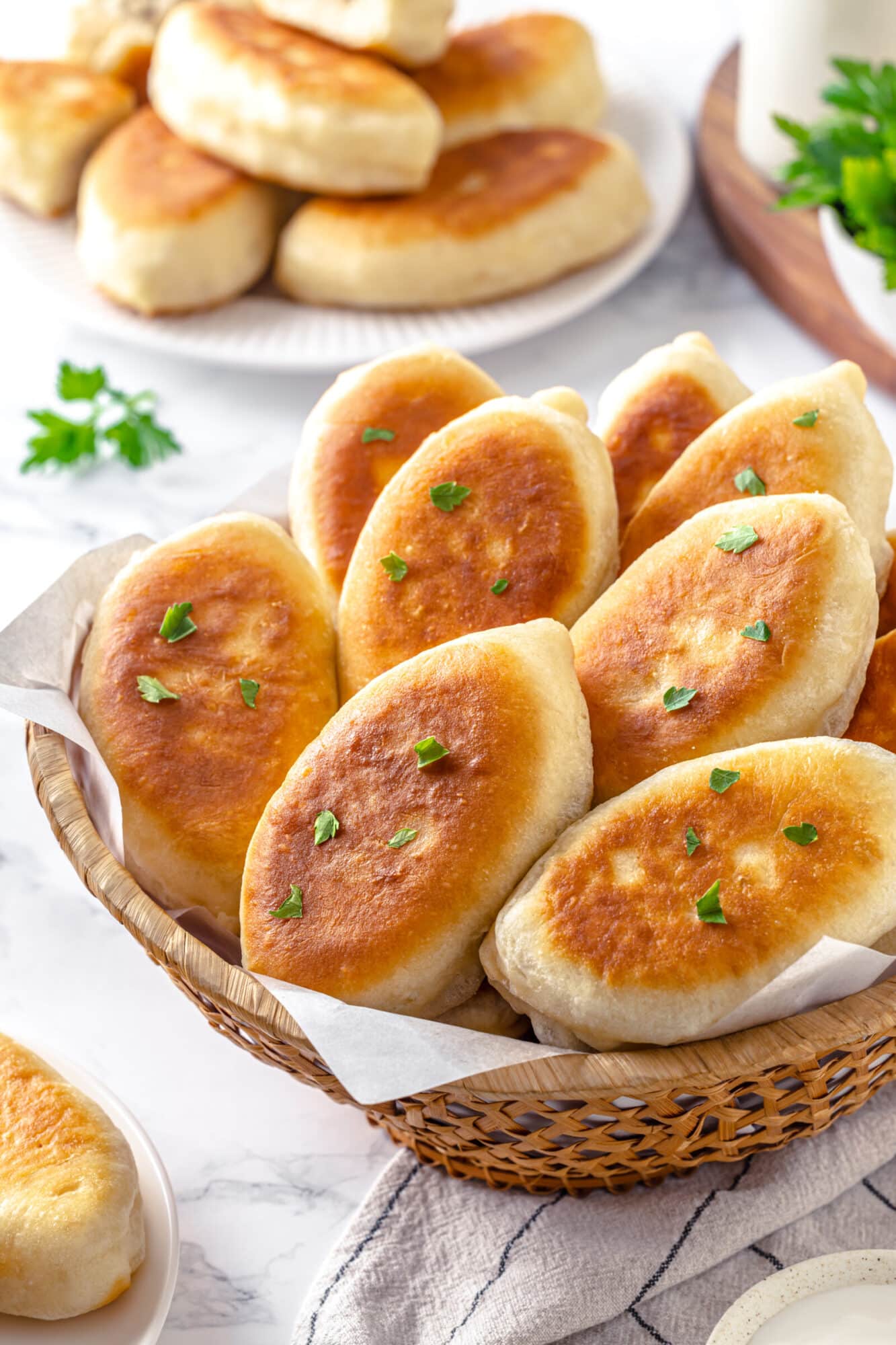 Piroshki in a woven bowl with parchment paper.