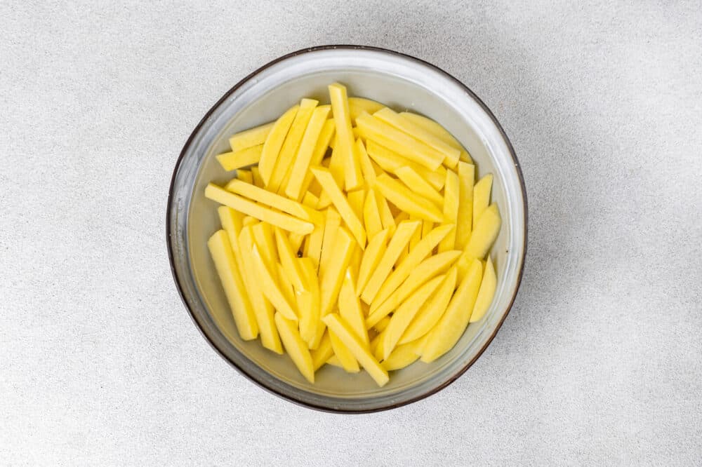 Potatoes soaking in a bowl of water.