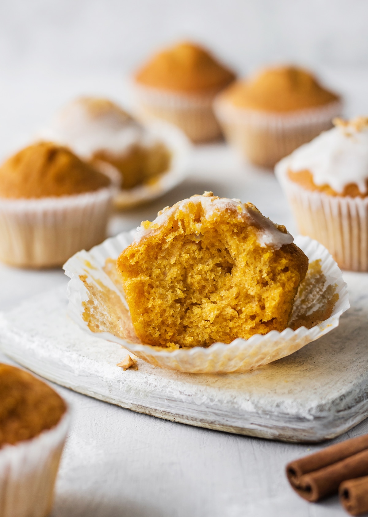 Bit-into pumpkin muffin with white glaze. 