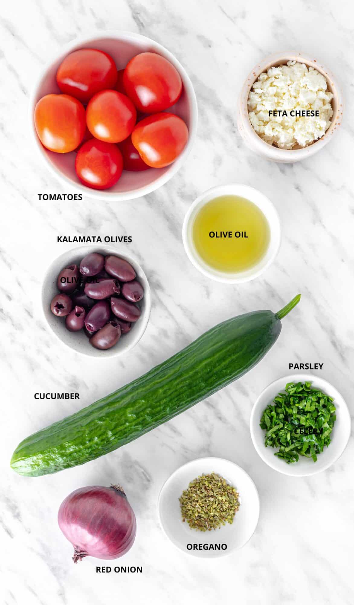 Quick Greek Salad ingredients- cucumber, tomatoes, feta cheese, olive oil, kalamata olives, parsley, red onion, and oregano.