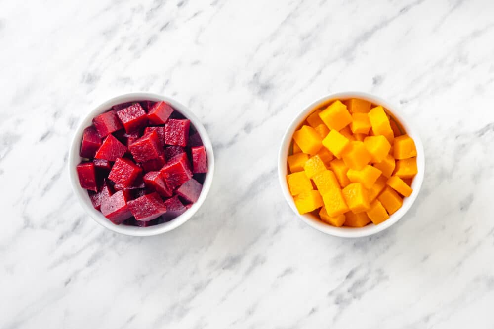 Cubed red beets in a white bowl, and cubed golden beet in a separate white bowl.