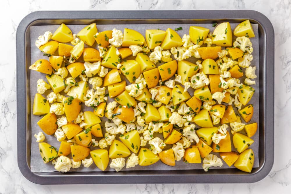 pre-roasted potato with cauliflower on an oven sheet pan.