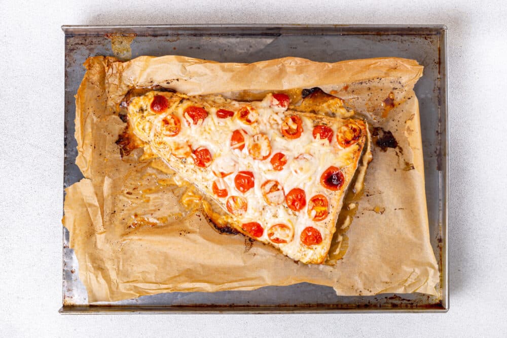 Oven baked salmon atop parchment paper just removed from the oven.