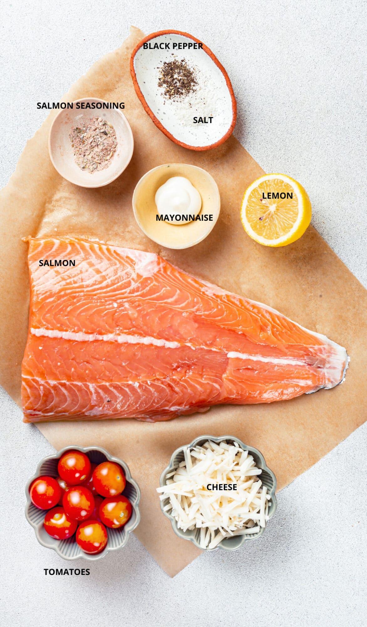 Salmon ingredients- black pepper, salt, salmon seasoning, lemon, mayonnaise, salmon, tomatoes, and cheese.